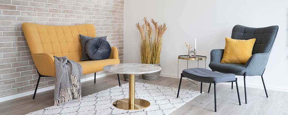 A Loft&Vintage webshop skandináv, nordic stílusú kollekciójának borítóképe, sárga skandináv kanapé és kék fotel márvány asztallal, párnák és szőnyeg, világos színű szobasarokban.