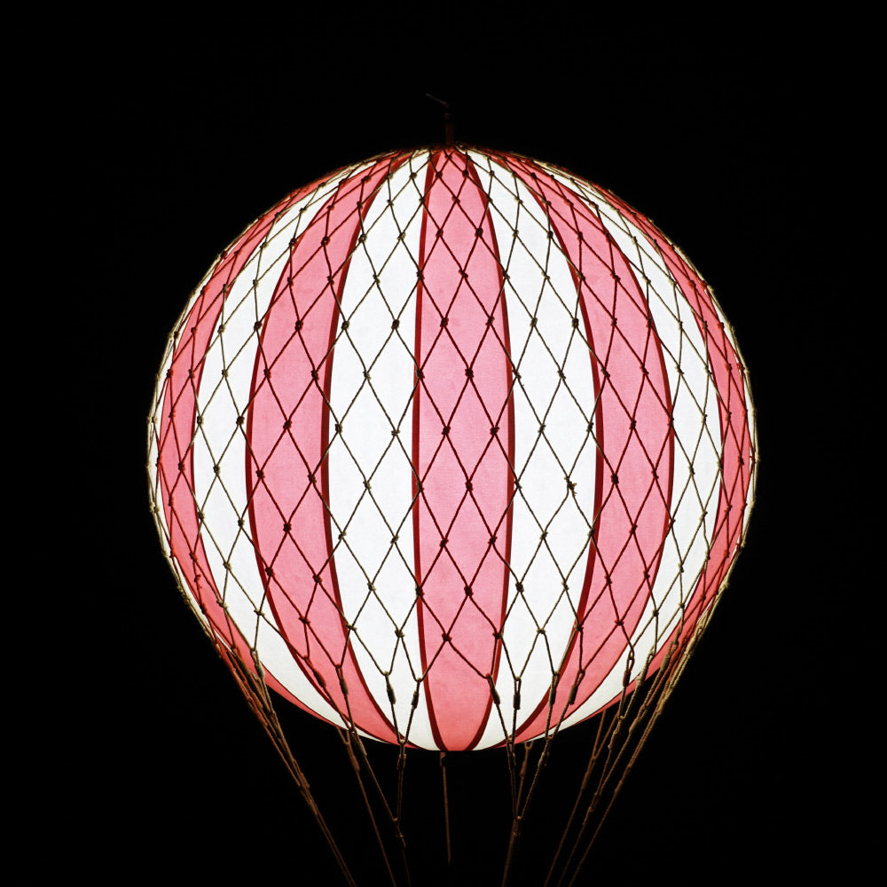 A piros-bézs színű LED-es hőlégballon fénye sötétben.