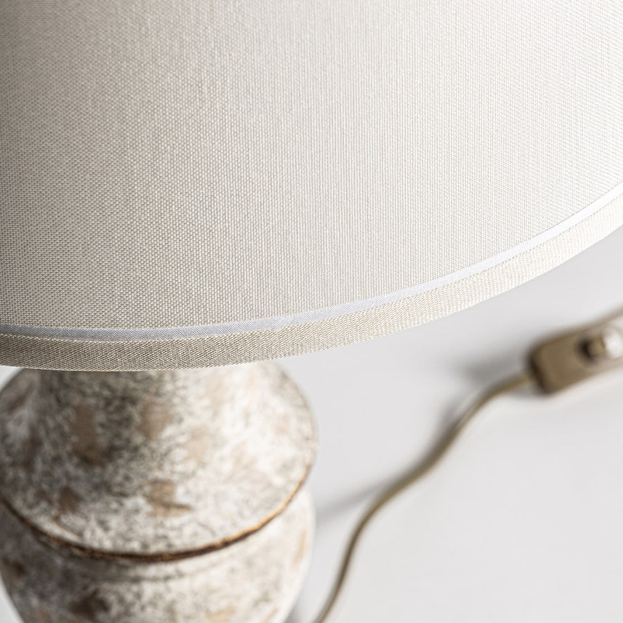 Close up of beige fabric lampshade with a distressed carved base from the Shabby Light table lamp
