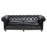 Háromszemélyes fekete Chesterfield bőrkanapé elölnézeti képe, klasszikus mélygombos háttámlával és görgős lábakkal.