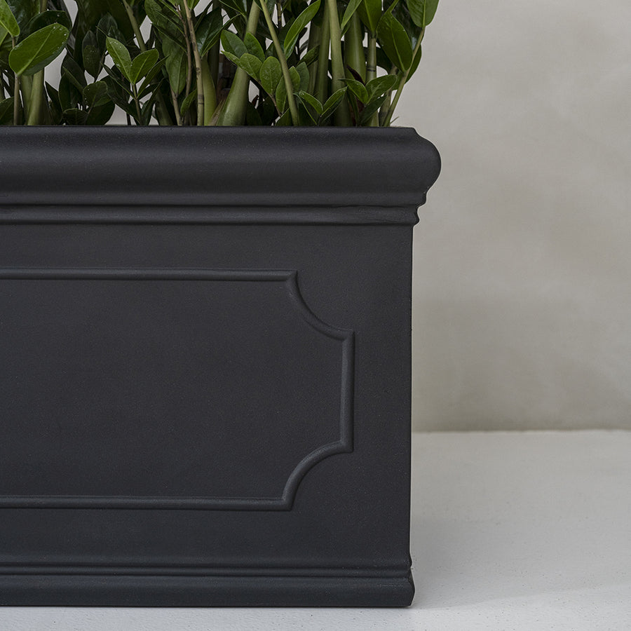 Heritage fekete fiberstone ültetőláda oldalrészlete finom élekkel és kerámia ihlette részletekkel, növényekkel a tetején.