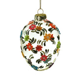 Plasztikus virágokkal díszített, függeszthető húsvéti üvegtojás.