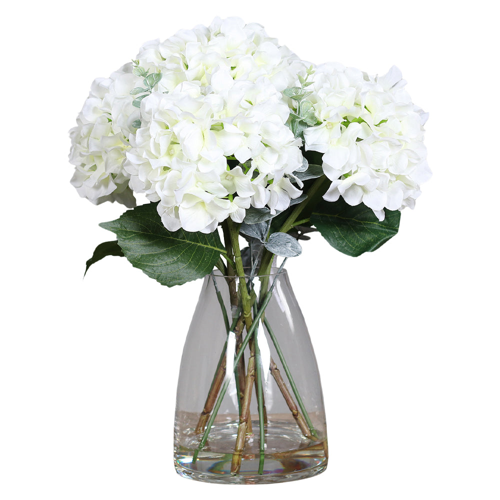 Víztiszta üvegvázában kialakított, krémszínű mű hortenzia virágcsokor.
