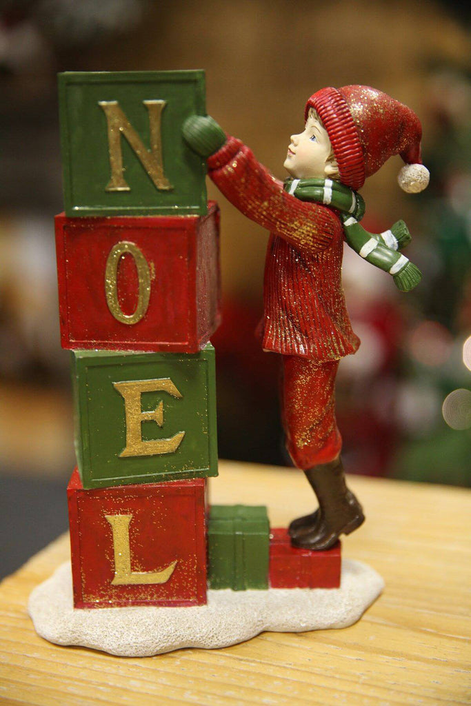 Téli kisfiúval díszített, "Noel" feliratú karácsonyi mécsestartó.