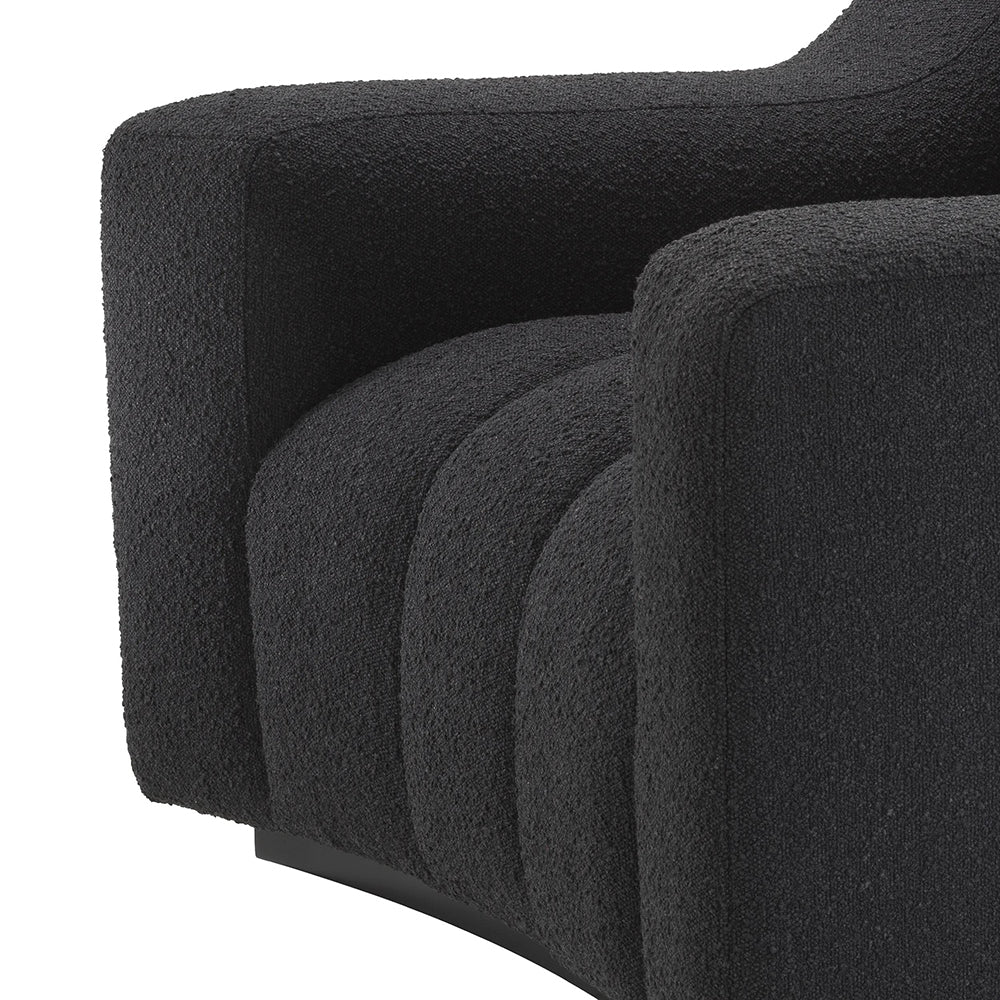 Fekete színű buklé szövettel kárpitozott dizájn fotel.