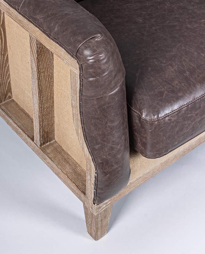 Loft stílusú, sötétbarna bőrrel kárpitozott kőrisfa kanapé karfa része.
