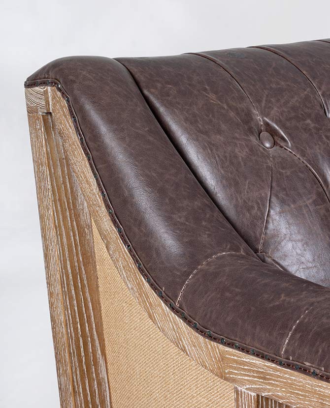 Loft stílusú, sötétbarna bőrrel kárpitozott kőrisfa kanapé karfa részlete.