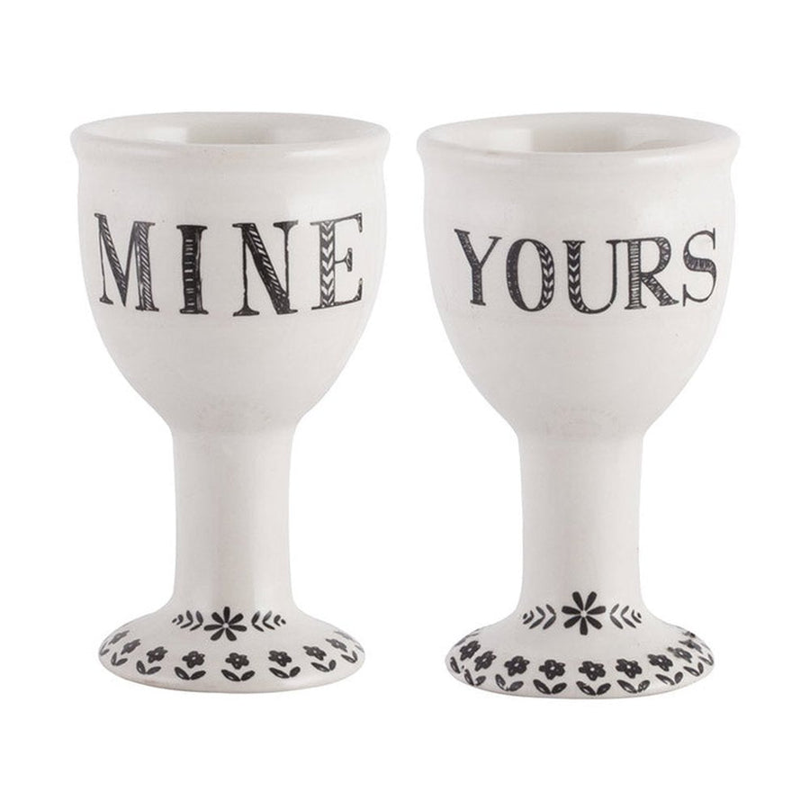 Pair of white ceramic egg cups with MINE and YOURS lettering and floral patterned bases
