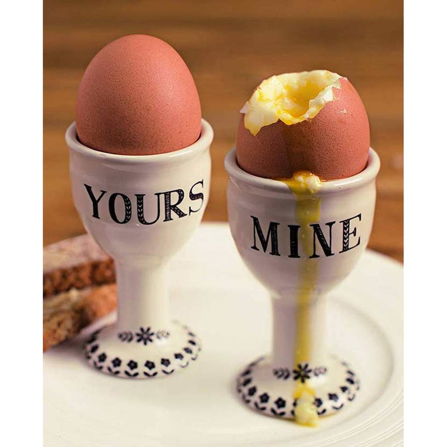 Two white ceramic egg cups labeled YOURS and MINE with eggs from the Stir It Up collection
