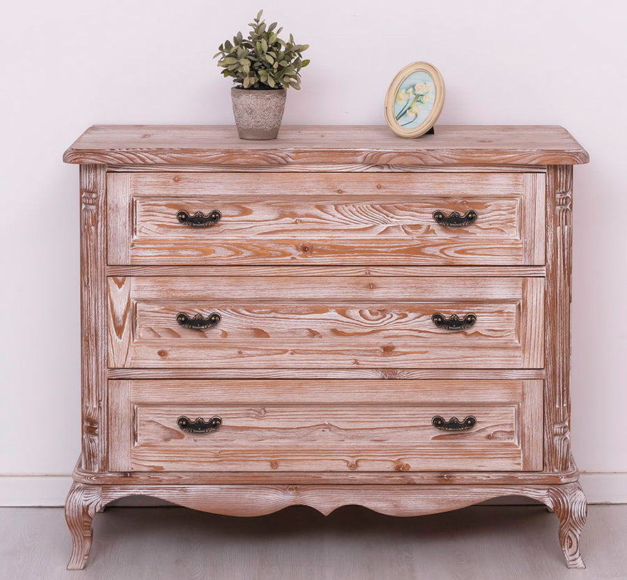 Fehérre meszelt shabby chic fenyő komód három fiókkal és díszes lábakkal a tetején növény és kerek óra