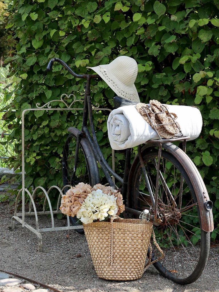 Bézs és krém színű mű hortenzia ágak gyékény táskában, kerékpárral.