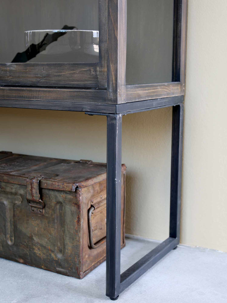 Fa vitrines szekrény fémkeretes lába, alatta régi bőrönd.