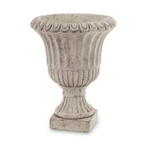 Antikolt felületű, szürke színű talpas cement kaspó.