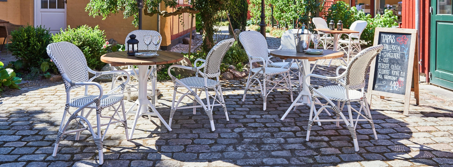 Kültéri fehér kávézó székek bisztró asztalokkal.
