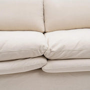 Bézs színű pamutvászon kárpitozású, kényelmes párnákkal ellátott kortárs kanapé..