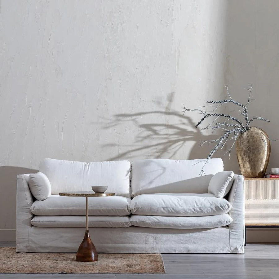 Bézs színű pamutvászon kárpitozású, kényelmes párnákkal ellátott kortárs kanapé.