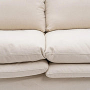 Bézs színű pamutvászon kárpitozású, kényelmes párnákkal ellátott kortárs kanapé.