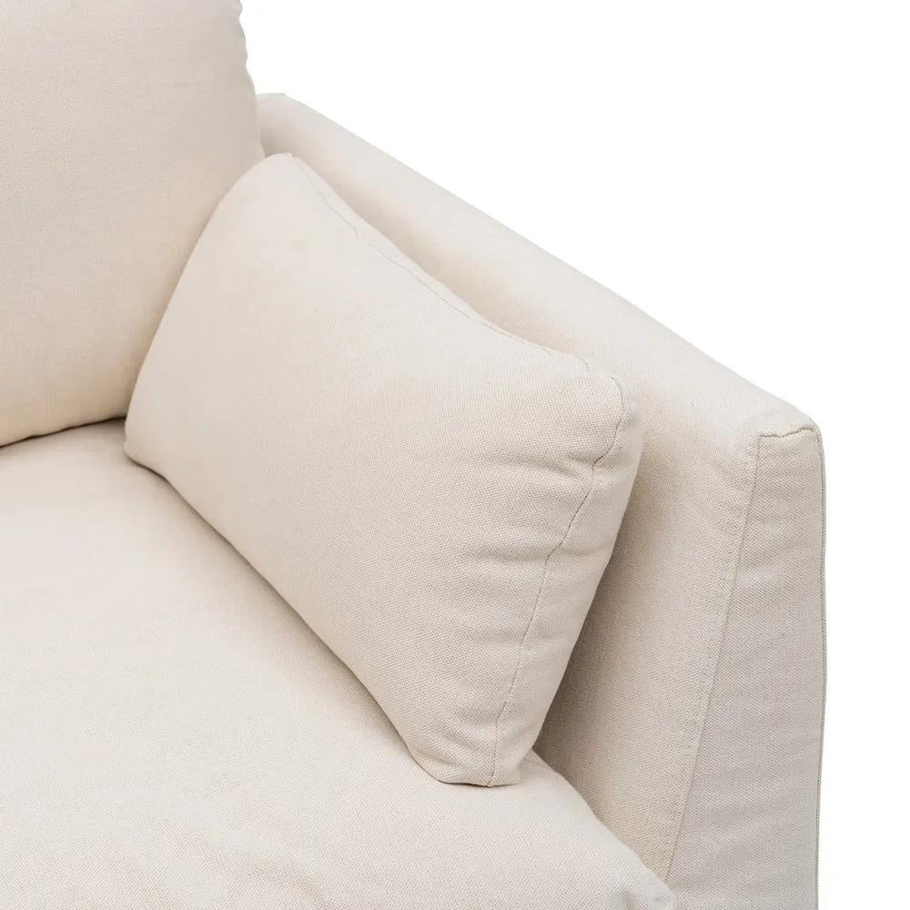 Bézs színű pamutvászon kárpitozású, kényelmes párnákkal ellátott kortárs kanapé.