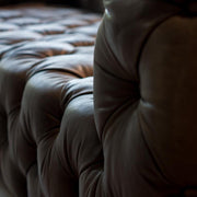 Szegecselt alumínium lemez borítású, montaigne fekete színű kecskebőrrel kárpitozott design kanapé.