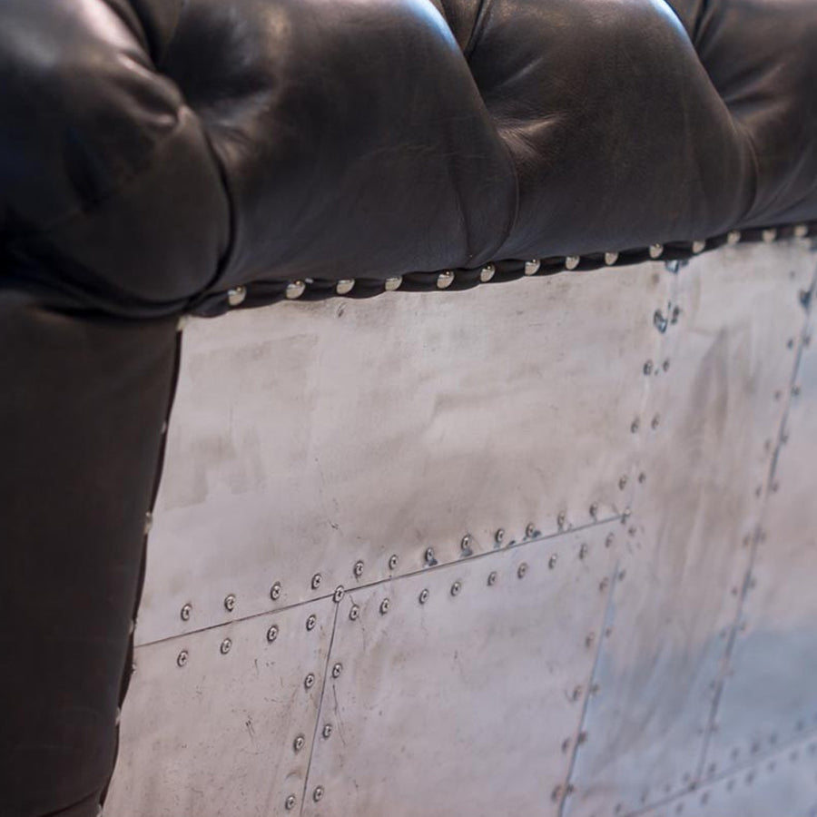 Szegecselt alumínium lemez borítású, montaigne fekete színű kecskebőrrel kárpitozott design kanapé.