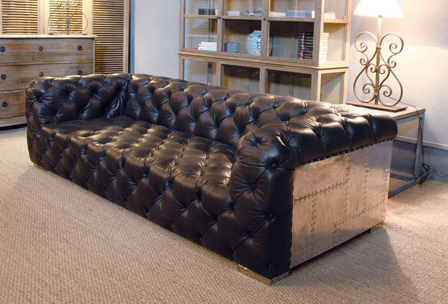 Szegecselt alumínium lemez borítású, montaigne fekete színű kecskebőrrel kárpitozott design kanapé.