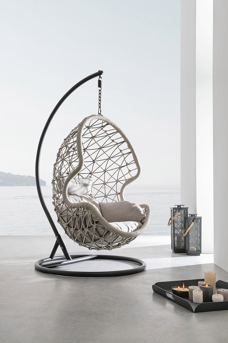 Kelly kortárs függőfotel fekete acél talppal és szürke párnákkal tengerpartra néző teraszon