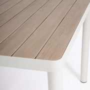 Az Ulises kollekció étkezőasztalának sarokrészlete a porszórt fehér színű peremmel, lábbal és a fahatású asztallappal