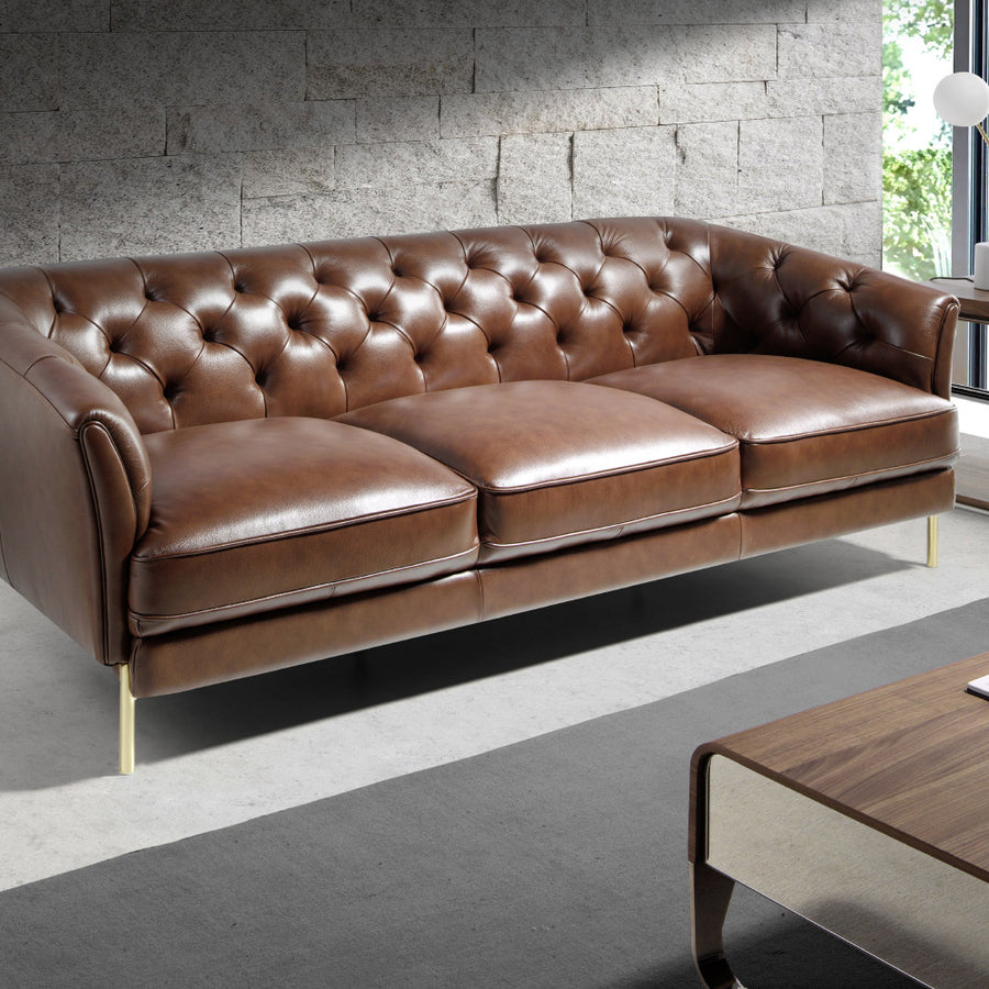 Kortárs stílusú, konyakszínű bőrrel kárpitozott, dizájn kanapé aranyszínű lábakkal.