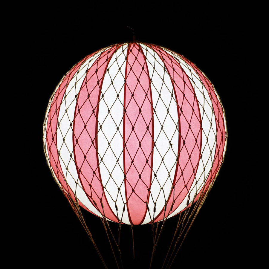 A piros-bézs színű LED-es hőlégballon fénye sötétben.