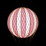 A piros-bézs színű LED-es hőlégballon fénye sötétben.