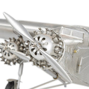 Fémből készült, részletgazdag, ezüstszínű Ford Trimotor repülőgép-modell állványon