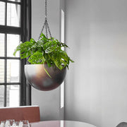 BAQ Gradient függeszthető kaspó Matt Coffee árnyalatban, zöld növénnyel, ablak előtt, étkezőasztal fölé akasztva.