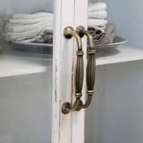 Régies fém fogantyú részlete krémszínű vitrines szekrényen