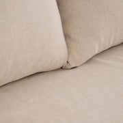 Bézs színű pamutvászon kárpitozású, kényelmes párnákkal ellátott kortárs kanapé..