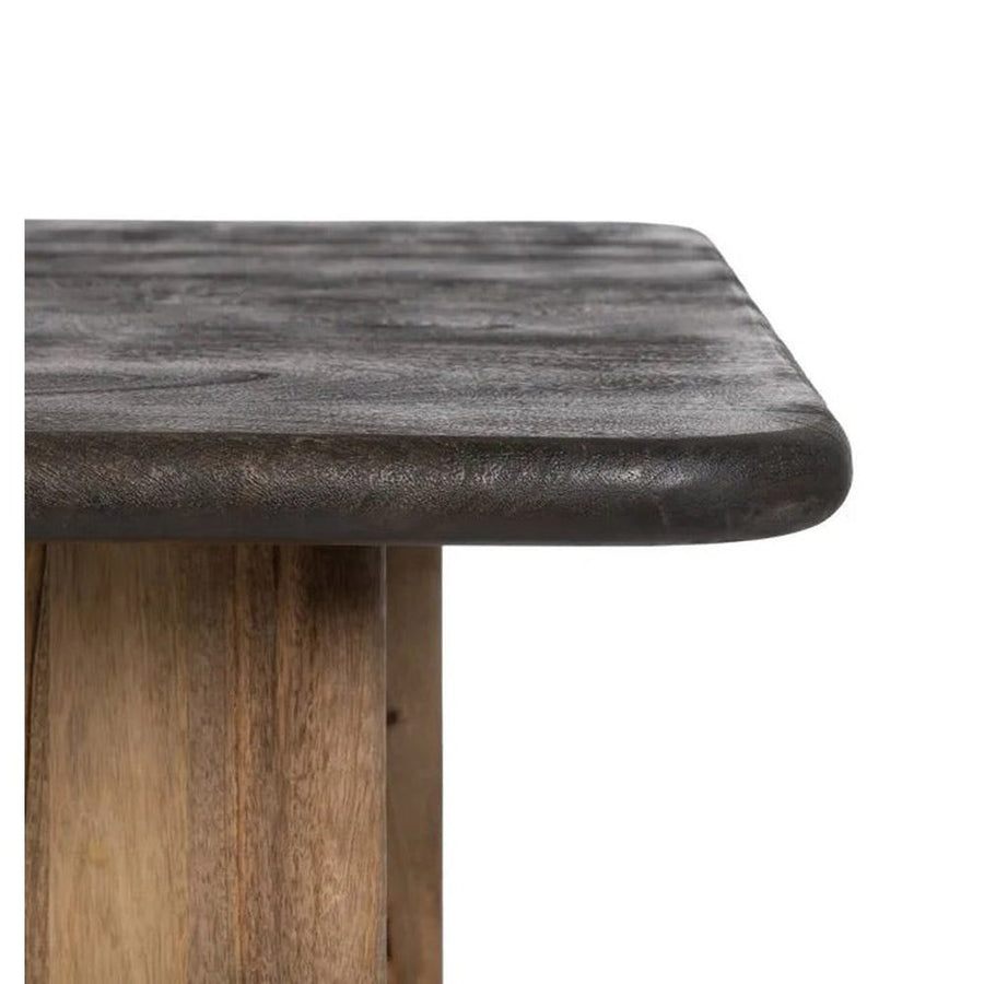 A kortárs stílusú, mangófából készült, natúr és sötétbarna színű étkezőasztal pereme.