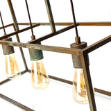 Cubic háromizzós függesztéklámpa részletképe antikolt sárgaréz felülettel, nyitott geometrikus kerettel és LED-izzókkal