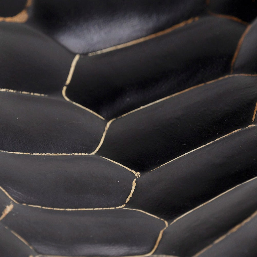 Kortárs stílusú, surafából készült kisasztal markáns faragású, fekete színű lábának részlete.