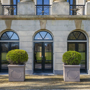 Heritage taupe óriás fiberstone kaspók formára nyírt örökzöldekkel, klasszikus épület előtt