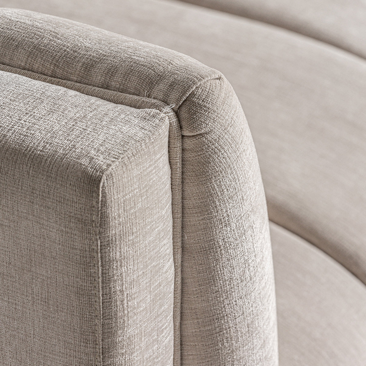 A kortárs stílusú, törtfehér színű kanapé karfa részlete.