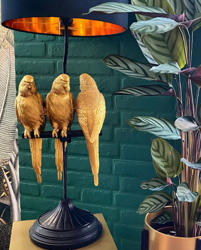 Aranyszínű papagáj figurákkal díszített, 79 cm magas, trópusi, glamour stílusú asztali lámpa, kék háttér előtt.