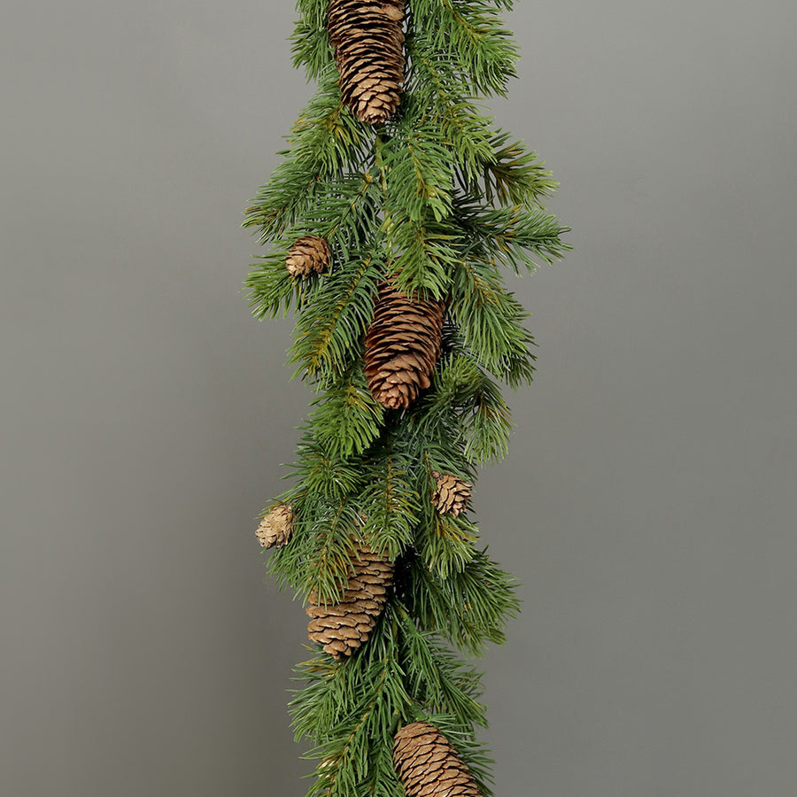 Élethű, zöld színű mű jegenyefenyő grland tobozokkal, szürke hátér előtt.
