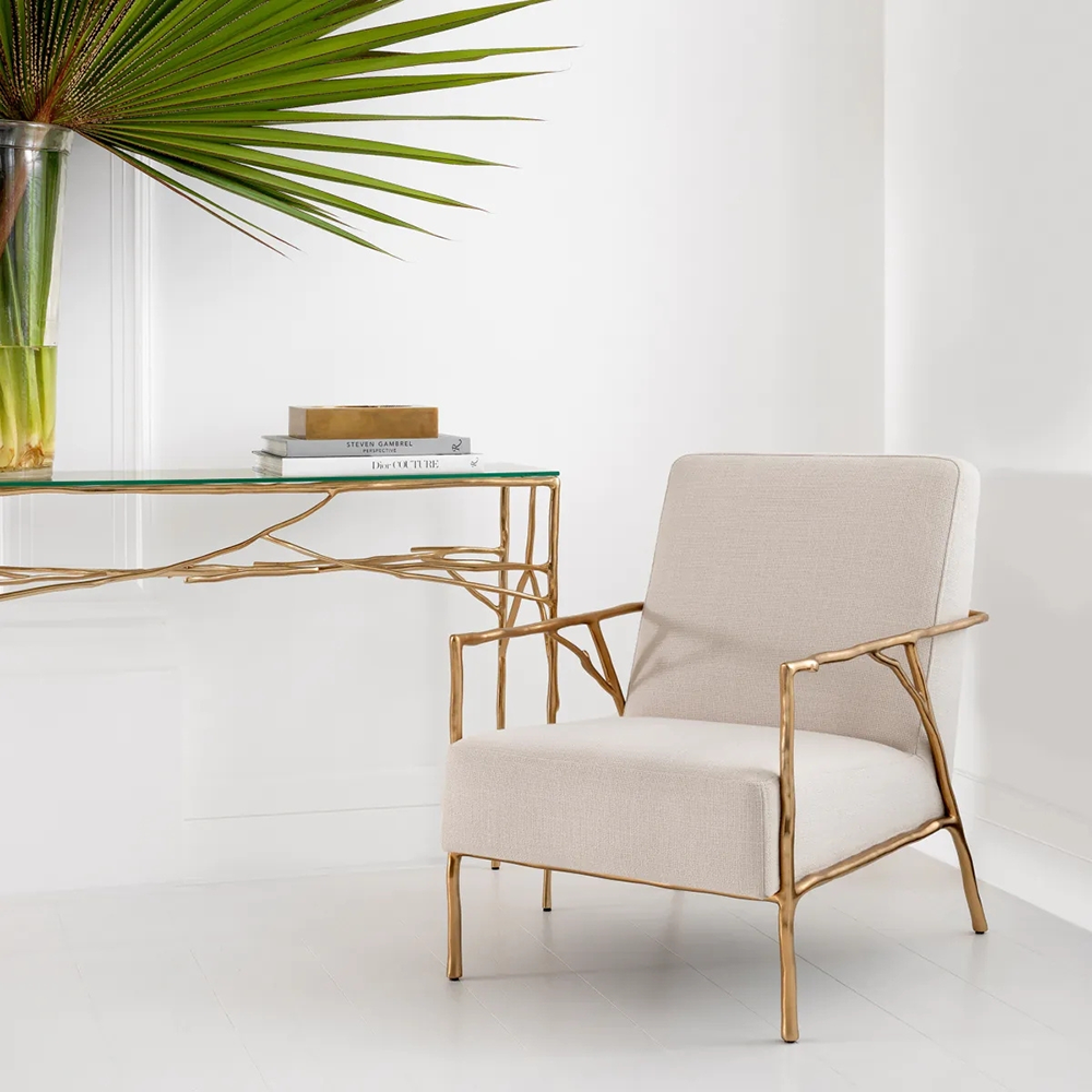 Antico bézs szövet design fotel elegáns enteriőrben, arany vázas konzolasztal mellett.