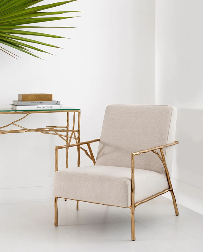 Antico bézs szövet design fotel elegáns enteriőrben, arany vázas konzolasztal mellett.