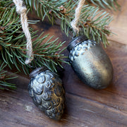 Toboz és makk formájú antik olívazöld karácsonyfadíszek juta akasztóval, fenyőág mellett