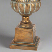 Antique Metals kaspó tömör fém talapzata patinázott rézszínű felülettel, klasszikus stílusú díszedény alsó része közelről.