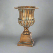 Antique Metals klasszikus stílusú, antik rézszínű fém kaspó teljes magasságban, patinázott felülettel és díszes talapzattal.
