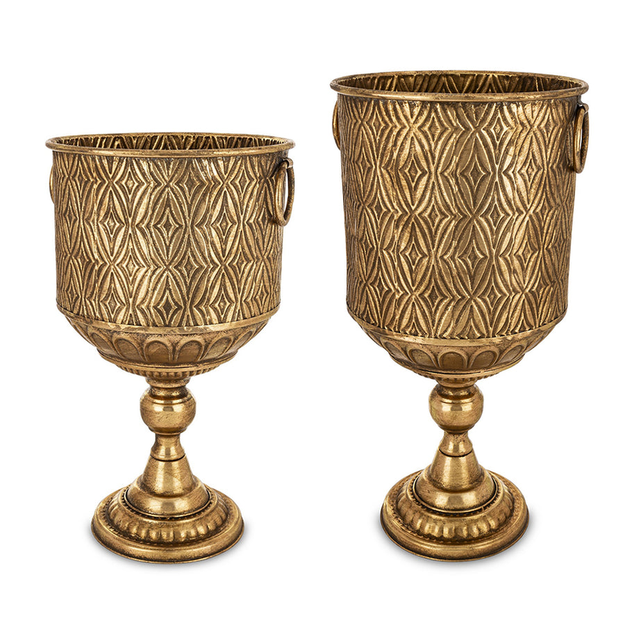 Két Antique Metals kaspó különböző méretben, antik aranyszínű fém felülettel és geometrikus mintázattal, klasszikus talapzaton.