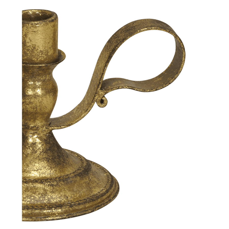 Részlet a rusztikus aranyszínű fém gyertyatartó hajlított fogantyújáról, antikolt felülettel.