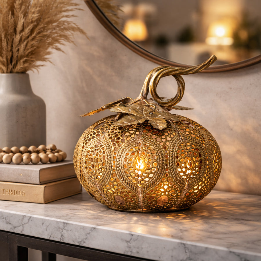 Aranyszínű, áttört mintázatú töklámpás komódon elhelyezve