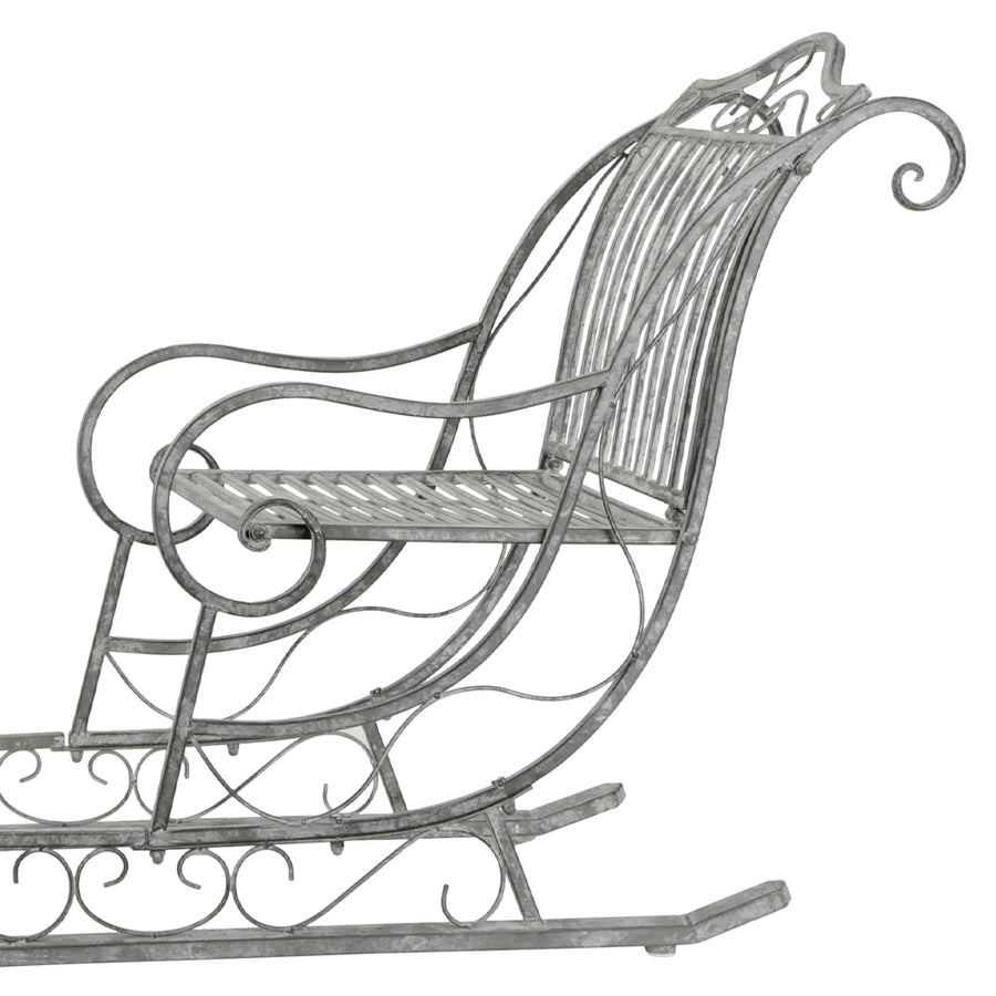 Dekoratív karácsonyi szán fém ülőfelülete és ívelt háttámlája, klasszikus vidéki stílusban.